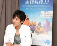 南極料理人のポスターを背景に座る堺雅人